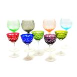 A group of Continental harlequin coloured glassware, comprising four stemmed wine glasses, engraved