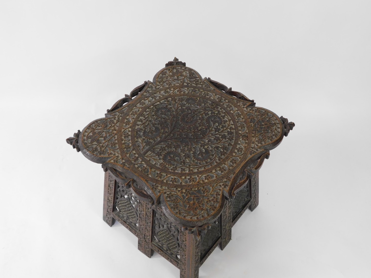 An Indian early 20thC hardwood folding occasional table, the top carved with Arabesques, the sides c - Image 3 of 4