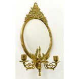 A Victorian brass girandole, the oval framed mirror inset bevelled glass, with a surmount cast with