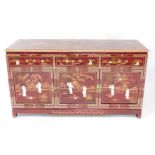 A Chinese red lacquer and 'Shibyama' sideboard, the top painted with bamboo, over three drawers abov
