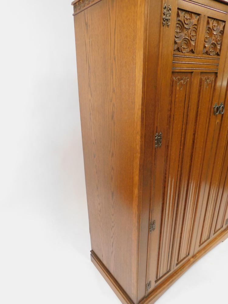 An Elizabethan style oak double wardrobe, with foliate and linen fold carved panelled doors, raised - Image 3 of 4