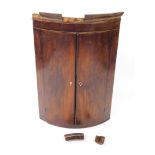A Georgian mahogany and line inlaid bow front hanging corner cupboard, the outswept pediment over tw