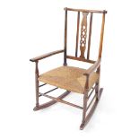 A Victorian Arts & Crafts oak rocking chair, with a Celtic knot splat, and rush seat, raised on turn