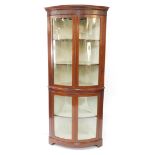 An Edwardian mahogany bowfront corner display cabinet, the outswept pediment with dentil moulding ab
