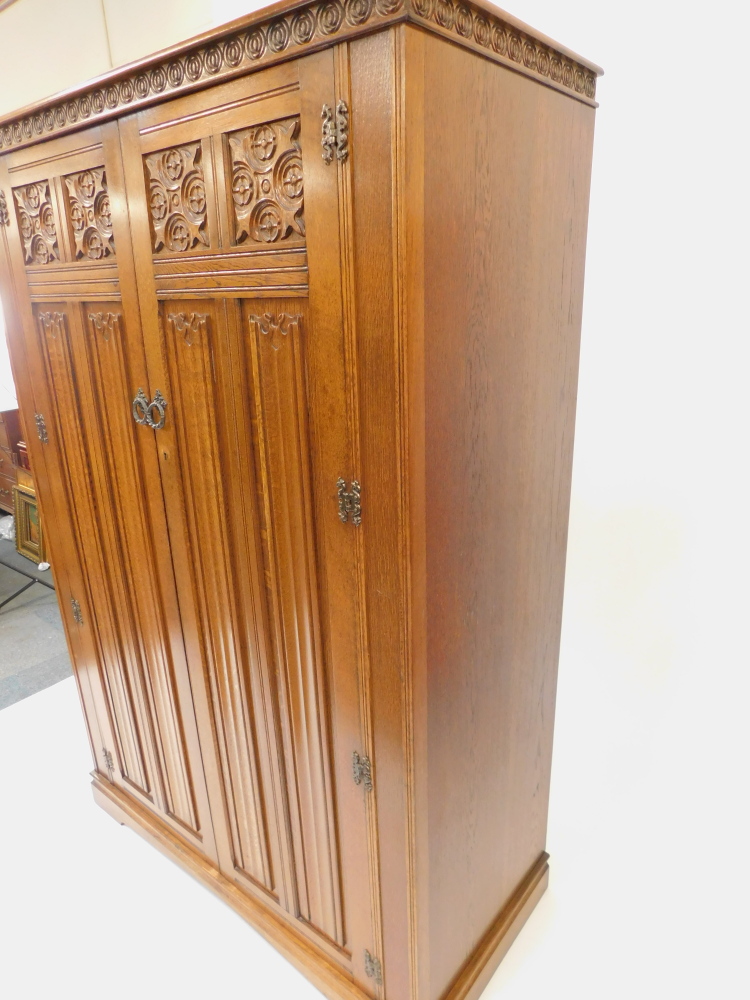 An Elizabethan style oak double wardrobe, with foliate and linen fold carved panelled doors, raised - Image 2 of 4