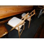 A set of four beech folding chairs, with seat cushions.