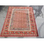 A machine made rug, red ground decorated with stags and a central square pattern, 135cm x 200cm.