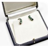 A pair of emerald and diamond set hoop earrings, each with a four row design of two emeralds and a t