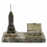 An Art Deco cigarette dispensing desk stand, formed with a cast spelter model of the Empire State Bu