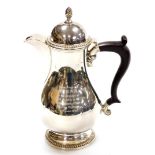 A George V silver coffee pot, with acorn finial top and rococo fluted spout, on an ebonised handle w