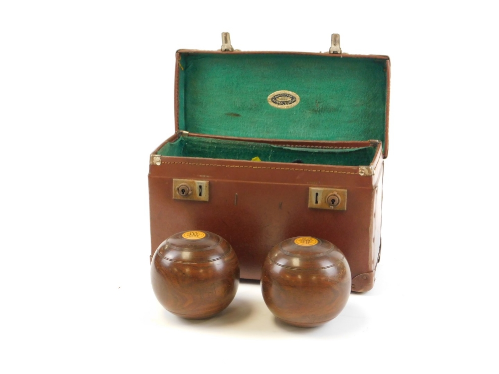 A cased set of carpet bowls, each carved wood detailed with crest emblem, in leather green lined cas