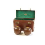A cased set of carpet bowls, each carved wood detailed with crest emblem, in leather green lined cas
