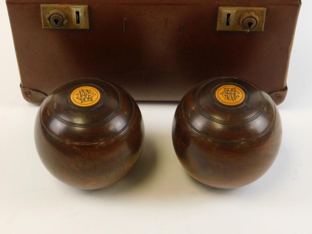 A cased set of carpet bowls, each carved wood detailed with crest emblem, in leather green lined cas - Image 2 of 2