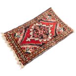 A Persian rug, with medallion border and central medallion panel, on tassel ends, 61cm x 39cm.