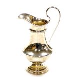 A George V silver cream jug, fluted and reeded body, on a stepped base, Birmingham 1923, 13cm high,