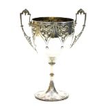 A Victorian silver two handled cup, with gothic stylised and pierced handles, and repousse floral pe