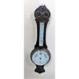 An Edwardian carved oak aneroid wheel barometer.