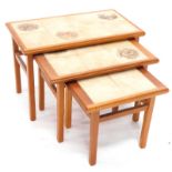 A nest of three teak tables, each with a painted tile design of badgers, white tailed Deer and