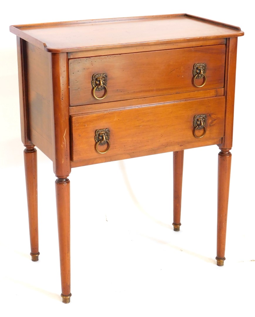 A French fruitwood bedside table, with a raised gallery, above two drawers, each with lion mask