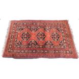 An Afghan rug, with a design of medallions and geometric devices on an orange ground, one wide and