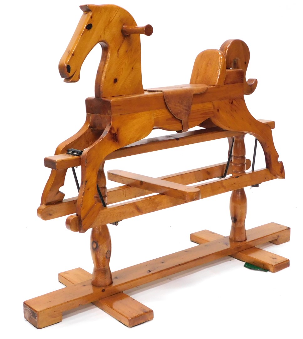 A carved pine child's rocking horse, with leather saddle and ebonised metal mounts, on a trestle