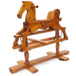 A carved pine child's rocking horse, with leather saddle and ebonised metal mounts, on a trestle