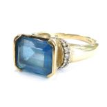 A modern dress ring, with rectangular set blue stone in tension setting, with tiny white stone set