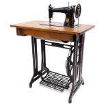 A Singer treadle sewing machine table, the fold-and-reveal machine numbered ED042387, on an oak