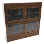 An oak two section bookcase in Globe Wernicke style, with a carved frieze above two pairs of
