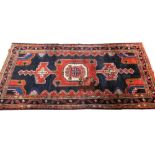 A Persian Hamadan type rug, with a central pole medallion in red on a navy ground with multiple