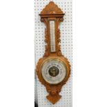 A late 19th/early 20thC carved oak aneroid barometer, with thermometer, 87cm high.