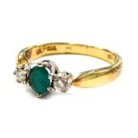 An 18ct gold emerald and diamond set dress ring, the central oval cut emerald in six claw setting,