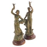 A pair of late 19thC French bronze patinated spelter figures, each modelled holding a bird and a