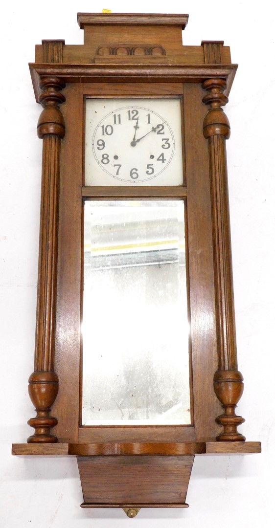 An early 20thC oak cased wall clock, the painted dial with Arabic numerals, the case with reeded