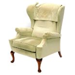 A green upholstered wingback reclining chair, on cabriole legs with pad feet. The upholstery in this