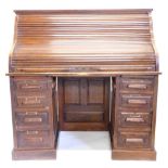 An oak roll top desk, the shaped tambour front enclosing a fitted interior of drawers and pigeon