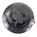 A late 19th/early 20thC Bakelite tape measure, made to simulate Whitby Jet, decorated with an owl,