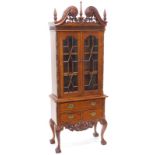 An eastern hardwood cabinet, the top with an elaborate pierced and carved cornice, above two