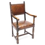 An oak and leather open armchair, on part turned legs.