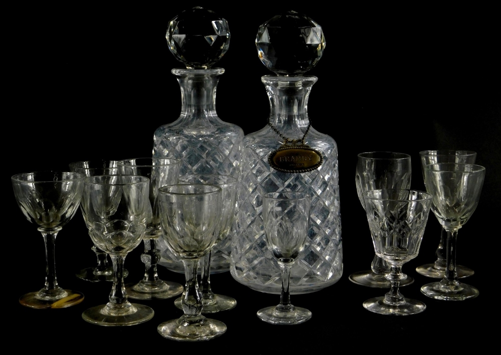 A pair of cut glass decanters and stoppers, and one silver decanter label for brandy, with beaded