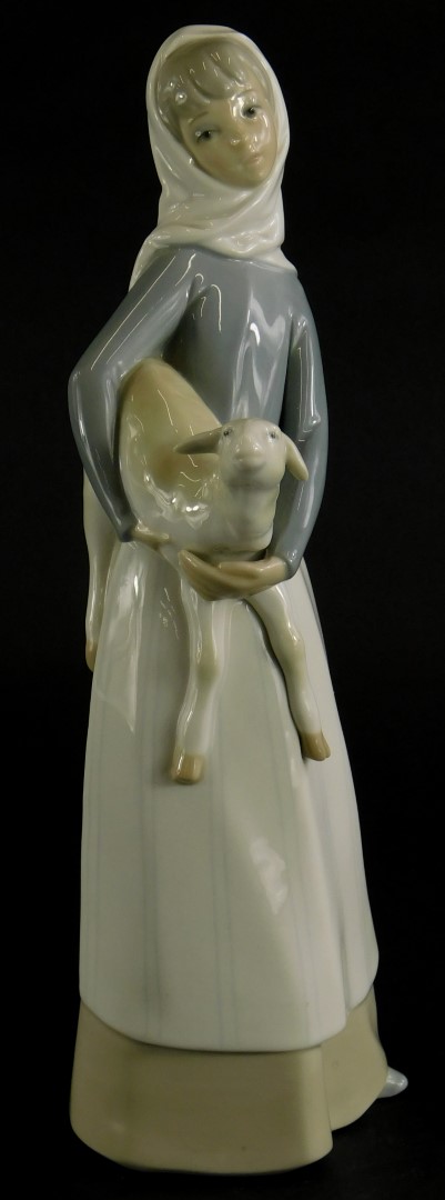 A Lladro porcelain figure of a lady holding a lamb, 27cm high.