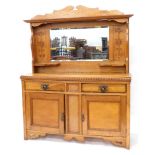 A late 19thC oak sideboard, the mirrored back with a shaped cornice, leaf carving and shelves, the