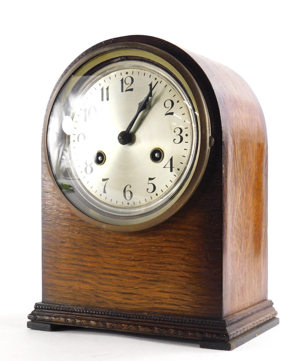 An early 20thC oak mantel clock, with an arched top and silver dial, 26cm high.