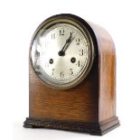 An early 20thC oak mantel clock, with an arched top and silver dial, 26cm high.