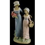 A Lladro porcelain figure group, of a lady with a young girl holding flowers, on oval base, 32cm