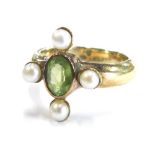 A modern dress ring, the central design set with peridot and four seed pearls, on a gold coloured