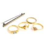 Four dress rings and a bar brooch, the bar brooch set with paste stones, on a white metal back,