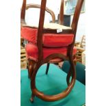 A pair of Victorian mahogany balloon back dining chairs, on cabriole legs, with overstuffed red