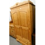 A pine double wardrobe, with top with a carved floral crest, the base with a single drawer, 176cm