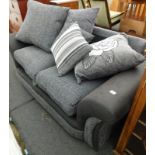 A modern two seater sofa, in grey upholstery, with various cushions.